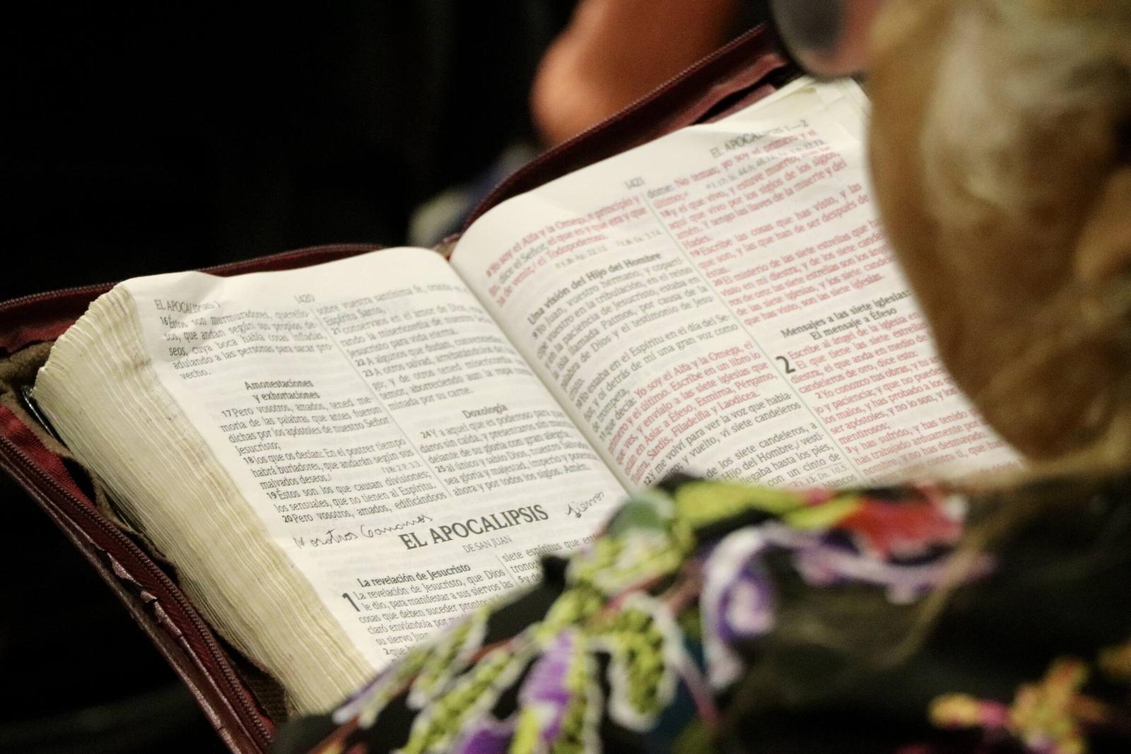 Una Biblia abierta en manos de una mujer, durante la reunión