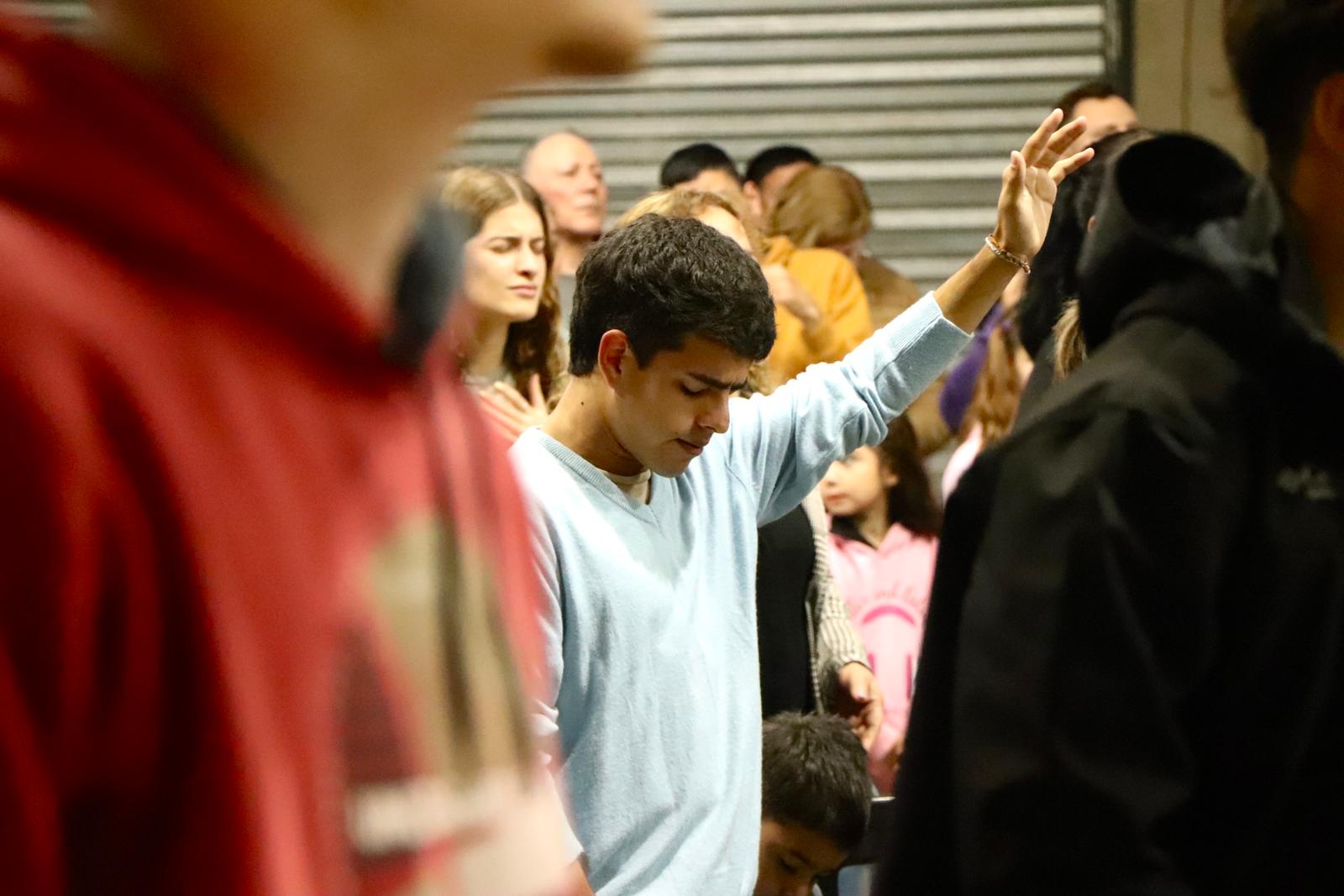 Un joven levanta la mano mientras la iglesia canta en la reunión del domingo